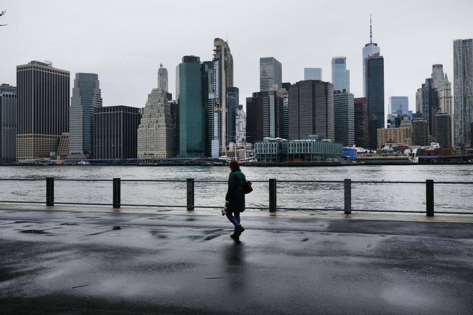 People walk in Brooklyn while lower Manhattan looms in the background, more than 1000 people have died of COVID-19 in the city. Source: Getty Images