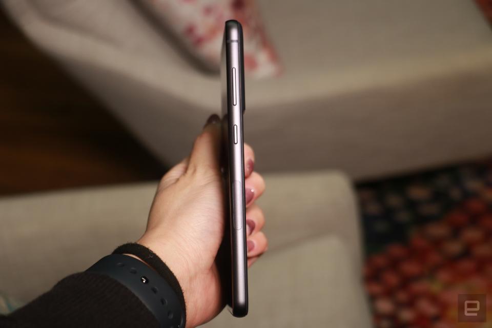 The Samsung Galaxy S21 FE in black held in mid-air with its right side facing the camera.