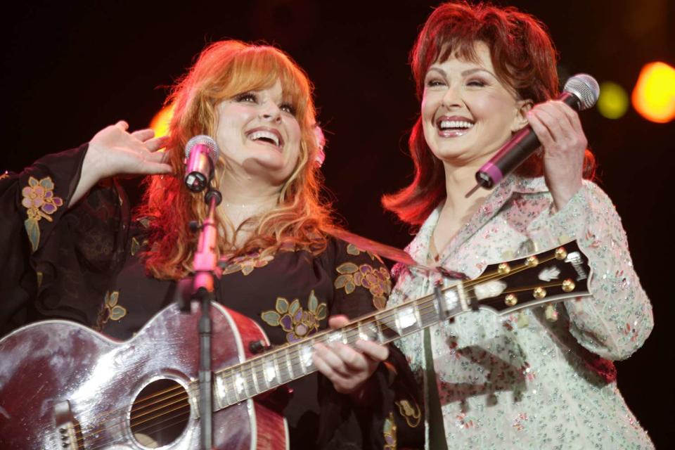 <p>Ed Rode/WireImage</p> Wynonna Judd (left) photographed while performing with Naomi Judd in Nashville