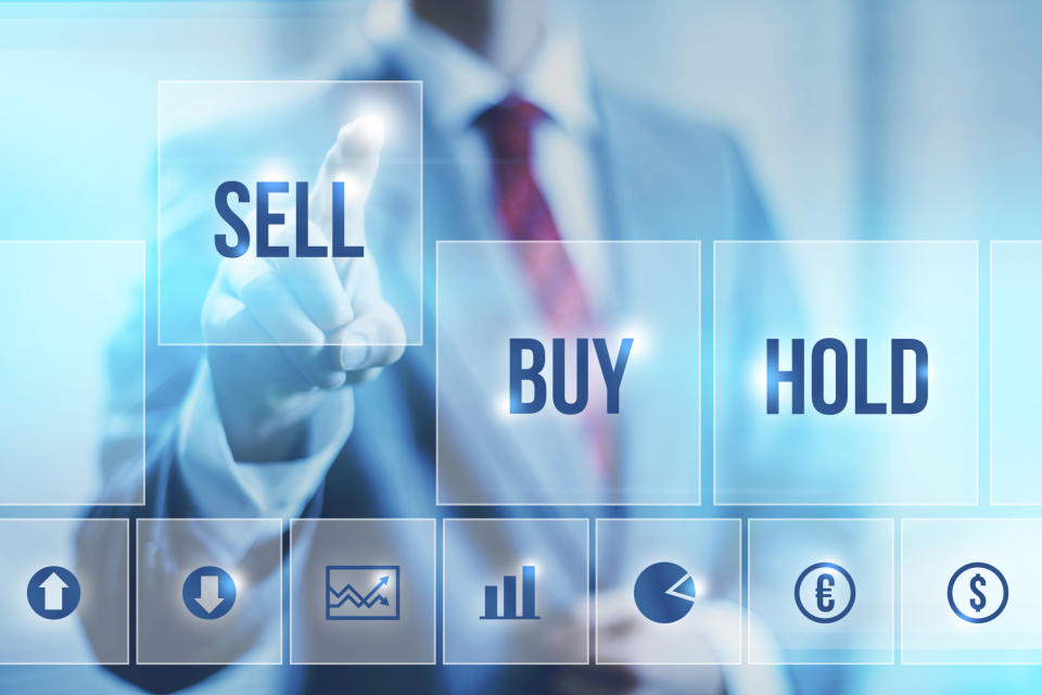 A businessman in a suit pressing the sell button on a digital screen.