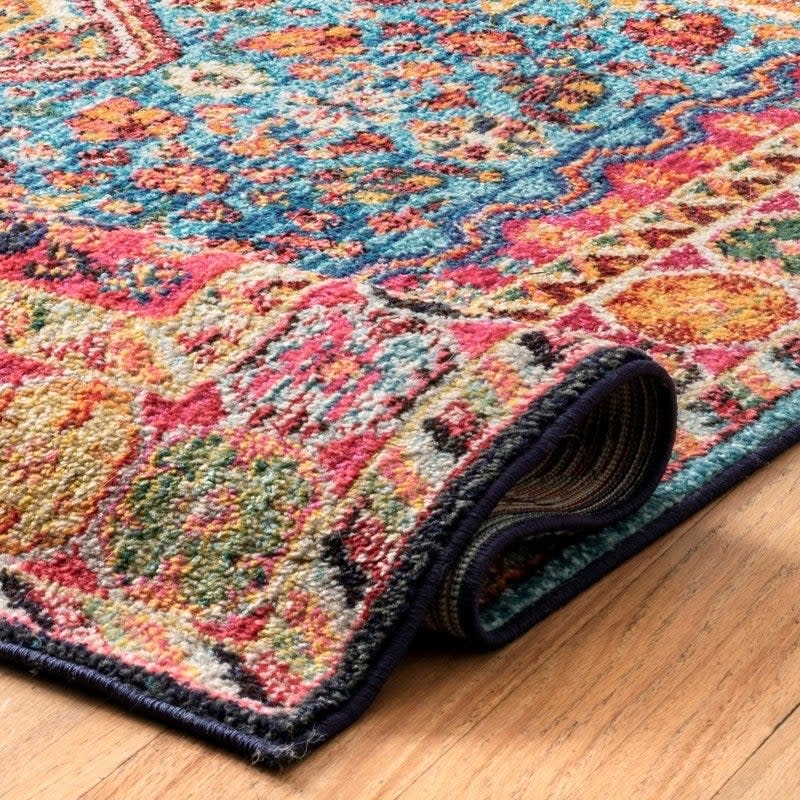 Decorative rug with intricate patterns, partially rolled up on a wooden floor