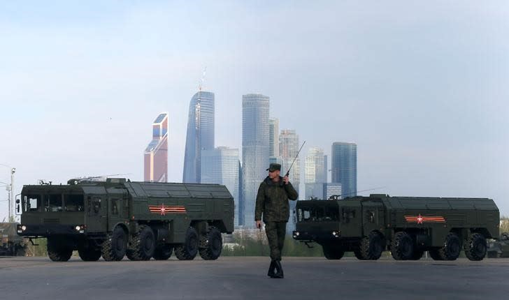 A Russian serviceman walks past Russian Iskander-M missile launchers before a rehearsal for the Victory Day parade, with the Moscow International Business Center also known as 