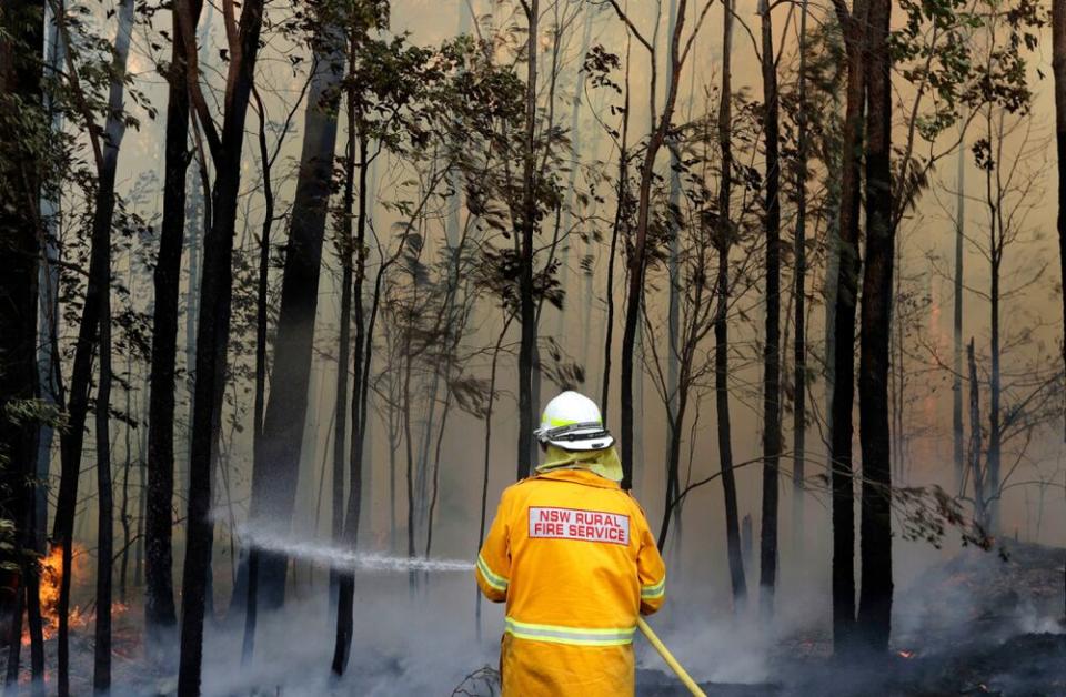 A firefighter extinguishes a blaze in Australia. Climate change is driving rising temperatures and natural disasters. | Rick Rycroft/AP/Shutterstock