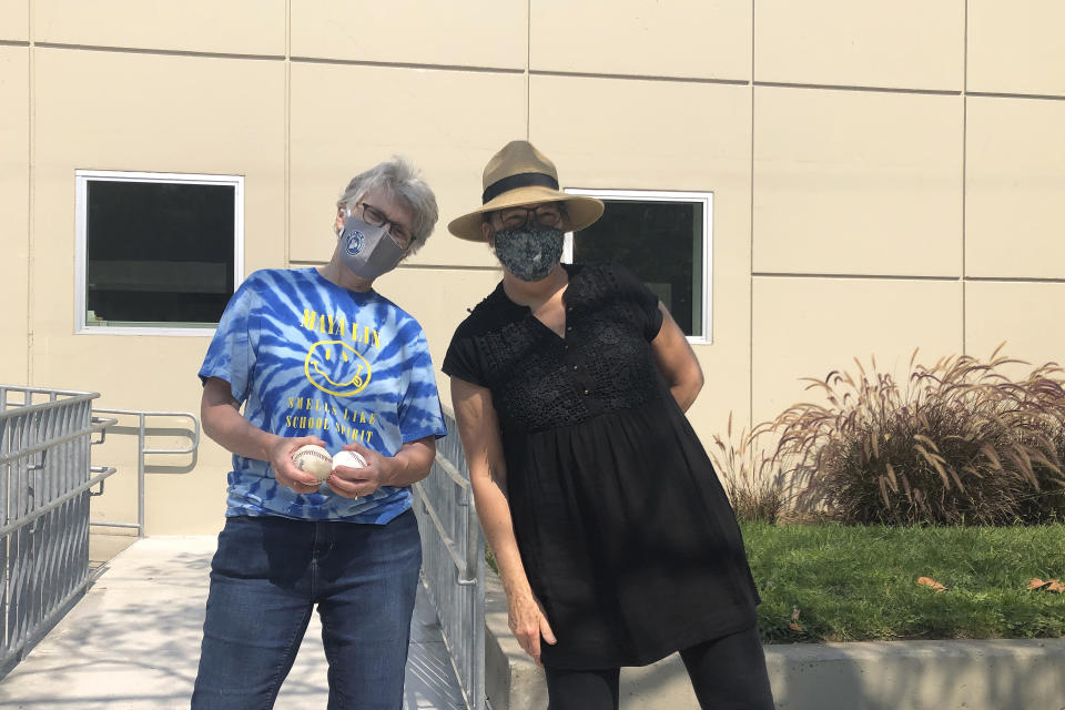 Maya Lin School Principal Judith Goodwin, left, holds foul balls alongside Alameda Arts after care co-founder Hazel Seiden outside of the elementary school in Alameda, Calif., Wednesday, Sept. 16, 2020. (AP Photo/Janie McCauley)