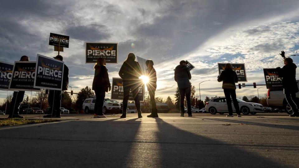 Supporters of Eagle Mayor Jason Pierce wave to commuters at rush hour at the corner of Eagle Road and Highway 44 on Tuesday.