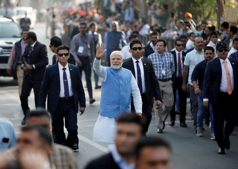 PM Modi waves to his supporters as he arrives to cast his vote, in Ahmedabad