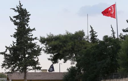 A Turkish flag flies over the Karkamis border crossing, as an Islamic State flag is seen at the customs office of Syria's Jarablus border gate in the background, in Karkamis, in Gaziantep province, Turkey August 1, 2015. REUTERS/Murad Sezer