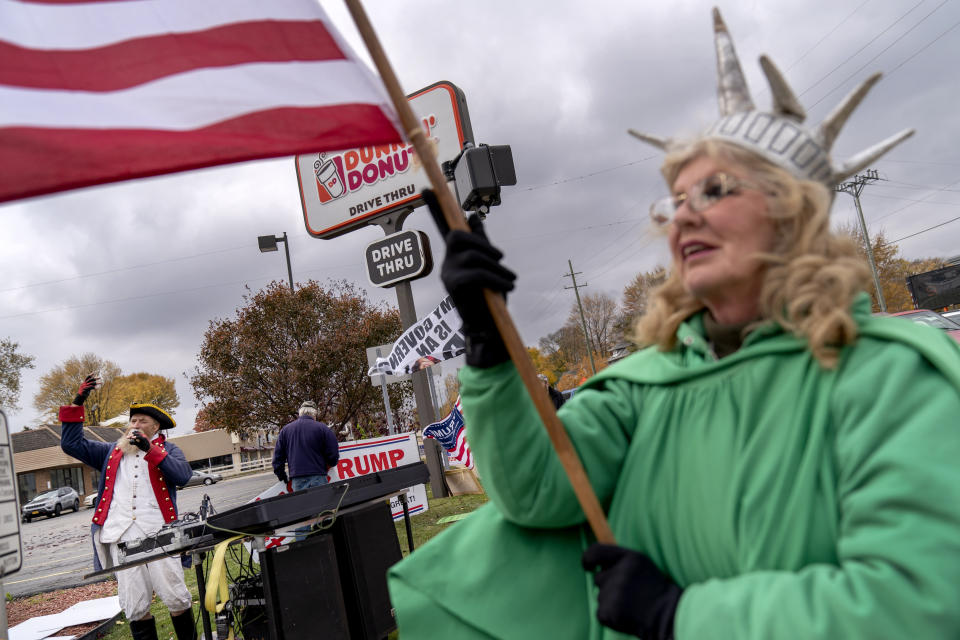 Trump supporters Carol Reed, dressed as the Statue of Liberty, right, and Matthew Woods, dressed as a Continental Army soldier, cheer at an intersection during a rally in Mount Clemens, Mich., Thursday, Oct. 29, 2020. About 7 in 10 voters say they are anxious about the election, according to an AP-NORC poll last month. Only a third are excited. Biden supporters were more likely than Trump voters to be nervous, 72% to 61%. (AP Photo/David Goldman)