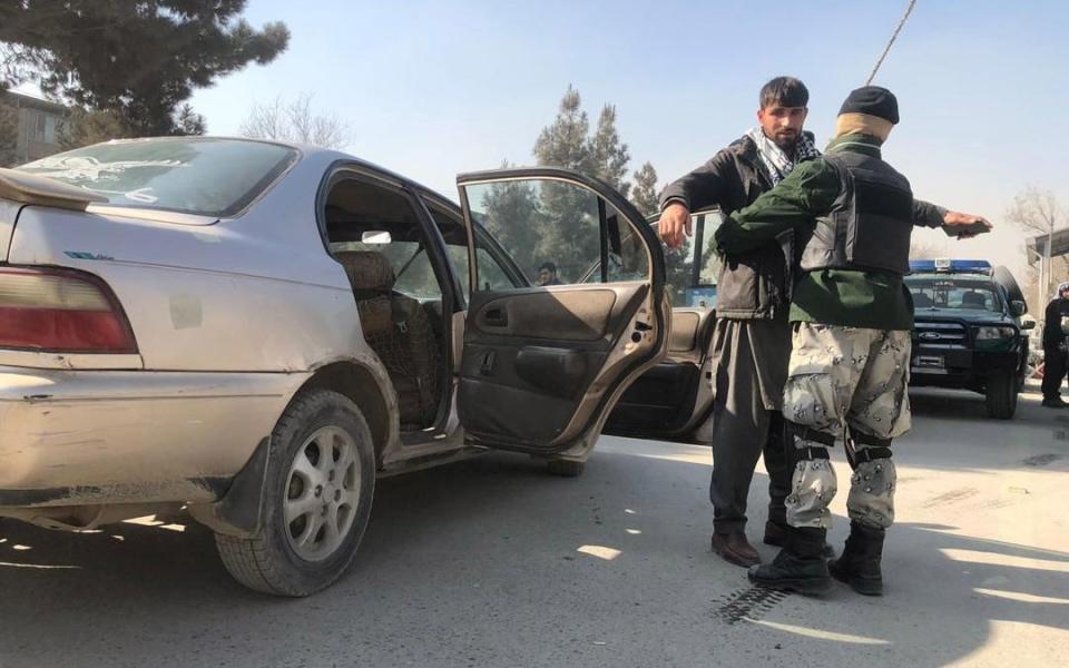 Afghan security officials check vehicles at a checkpoint in Kabul, Afghanistan, - Shutterstock/Shutterstock