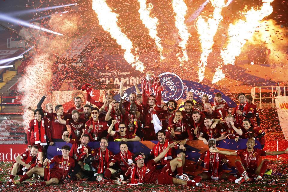 Liverpool's Jordan Henderson holds the English Premier League trophy aloft after it was presented following the Premier League soccer match between Liverpool and Chelsea at Anfield stadium in Liverpool, England, Wednesday, July 22, 2020. (Phil Noble/Pool via AP)