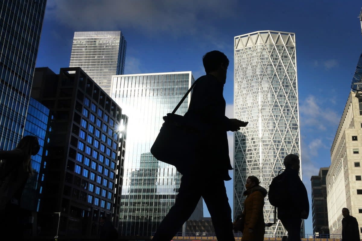 Office workers and commuters walk through Canary Wharf in London  (PA Archive)