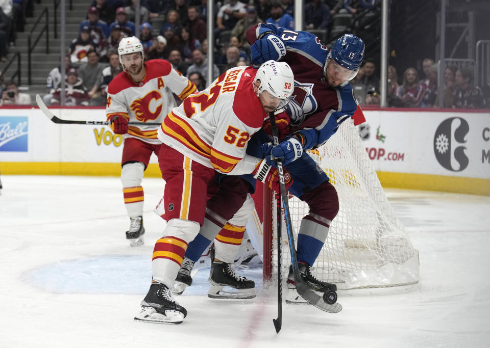Calgary Flames defenseman MacKenzie Weegar, front left, battles for control of the puck with Colorado Avalanche right wing Valeri Nichushkin, right, in the first period of an NHL hockey game Monday, Dec. 11, 2023, in Denver. (AP Photo/David Zalubowski)