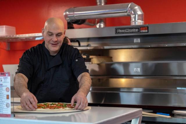 Erik Borger, the owner of Pizza Tascio, fixes a spicy pepperoni pizza.