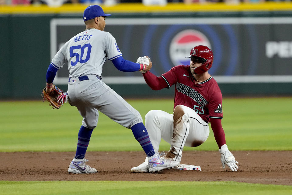 Los Angeles Dodgers' Mookie Betts (50) helps Arizona Diamondbacks' Christian Walker up after Walker was forced out on a double play hit by Eugenio Suárez during the third inning of a baseball game, Monday, April 29, 2024, in Phoenix. (AP Photo/Matt York)
