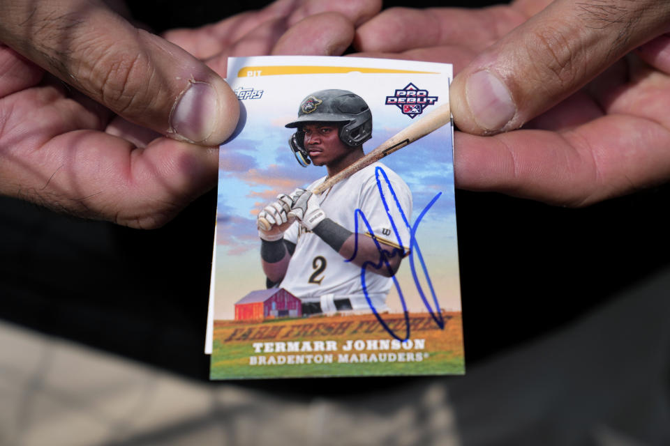 A fan holds an autographed baseball card of Pittsburgh Pirates second baseman Termarr Johnson before a spring training baseball game between the Pirates and the Detroit Tigers Saturday, March 9, 2024, in Lakeland, Fla. (AP Photo/Charlie Neibergall)