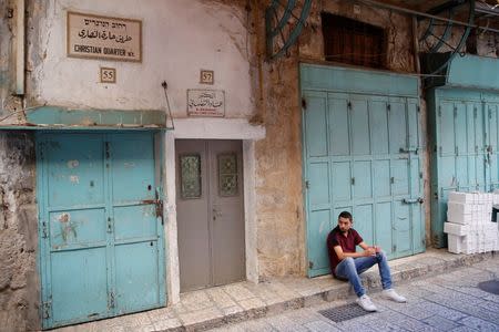 A man sits on a curb in the Christian Quarter of Jerusalem's Old City June 21, 2016. REUTERS/Ronen Zvulun