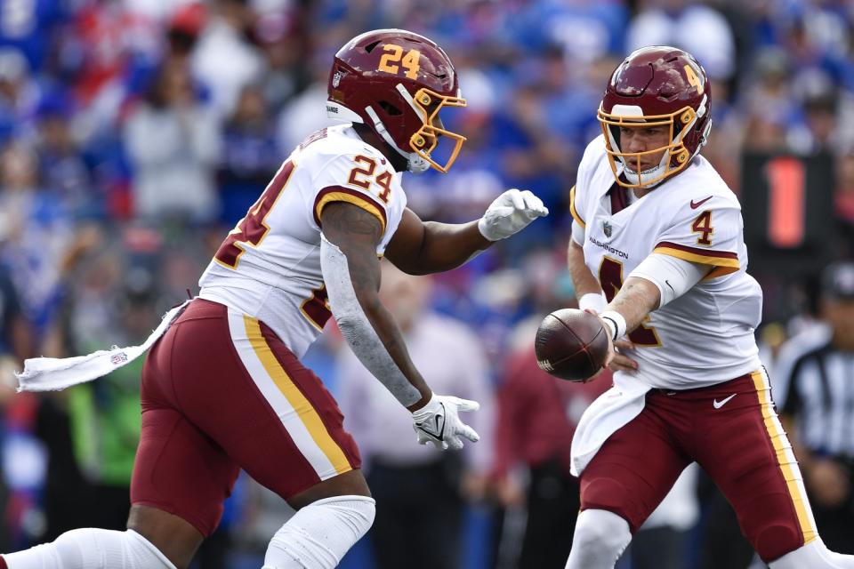 Washington Football Team quarterback Taylor Heinicke hands the ball to running back Antonio Gibson.