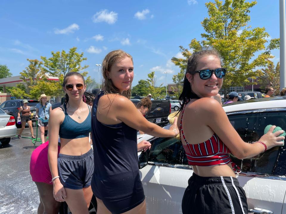 McKenzie Toon, 16, Jalee King, 17, and Samara Griffin, 16, all said it was a little toasty outside but the water made it better at the Hardin Valley Academy Band car wash at Food City on Middlebrook Pike Saturday, July 23, 2022.