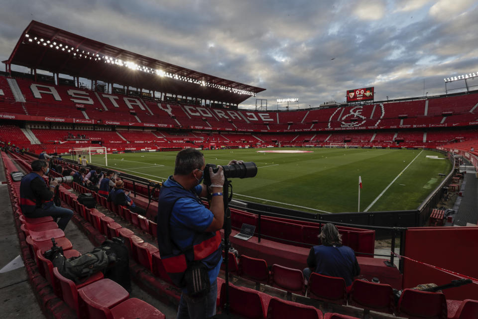 Press photographers shoot pictures before the start of the Spanish La Liga soccer match between Sevilla and Betis in Seville, Spain, Thursday, June 11, 2020. With virtual crowds, daily matches and lots of testing for the coronavirus, soccer is coming back to Spain. The Spanish league resumes this week more than three months after it was suspended because of the pandemic, becoming the second top league to restart in Europe. The Bundesliga was first. The Premier League and the Italian league should be next in the coming weeks. (AP Photo)