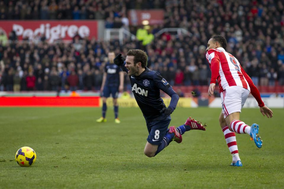 Manchester United's Juan Mata, centre, is brought down by Stoke's Peter Odemwingie during their English Premier League soccer match at the Britannia Stadium, Stoke, England, Saturday Feb. 1, 2014. (AP Photo/Jon Super)