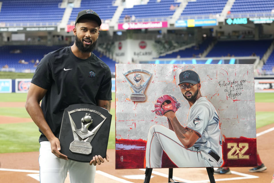 Miami Marlins starting pitcher Sandy Alcantara, left, holds his Cy Young Award plaque as he poses with his portrait during a ceremony before a baseball game against the Minnesota Twins, Monday, April 3, 2023, in Miami. (AP Photo/Lynne Sladky)