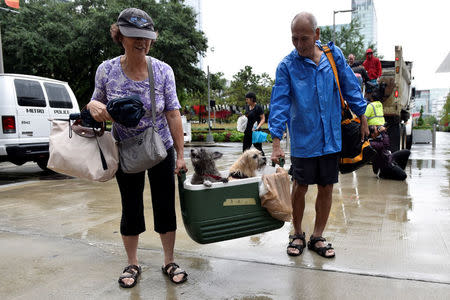 A couple of evacuees carry their dogs into the the George R. Brown Convention Center after Hurricane Harvey inundated the Texas Gulf coast with rain causing widespread flooding, in Houston, Texas, U.S. August 27, 2017. REUTERS/Nick Oxford