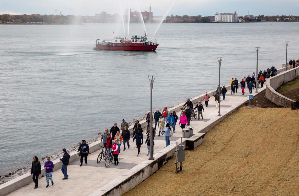 Dozens of pedestrians walk during the Uniroyal Promenade ribbon-cutting ceremony on Detroit’s RiverWalk in Detroit on Saturday, Oct. 21, 2023. The new Uniroyal Promenade completes the 3.5-mile-long RiverWalk and provides access to Belle Isle.