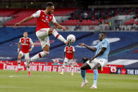 Arsenal's Pierre-Emerick Aubameyang, left, is airborne as he kicks at the ball away from Manchester City's Benjamin Mendy during the FA Cup semifinal soccer match between Arsenal and Manchester City at Wembley in London, England, Saturday, July 18, 2020. (AP Photo/Matt Childs,Pool)