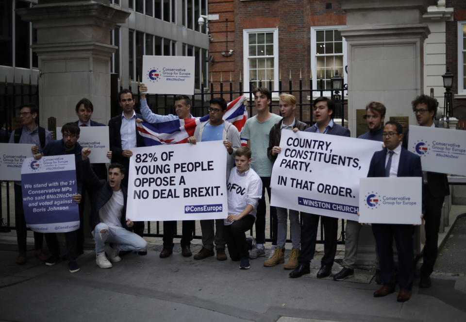 Young Conservative party members hold signs as they demonstrate outside Conservative Party Campaign Headquarters in London, Wednesday, Sept. 4, 2019. With Britain's prime minister weakened by a major defeat in Parliament, defiant lawmakers were moving Wednesday to bar Boris Johnson from pursuing a "no-deal" departure from the European Union. (AP Photo/Matt Dunham)