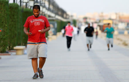 A Saudi man uses his smartphone as he walks on a sidewalk in Riyadh, Saudi Arabia September 21, 2017. REUTERS/Faisal Al Nasser