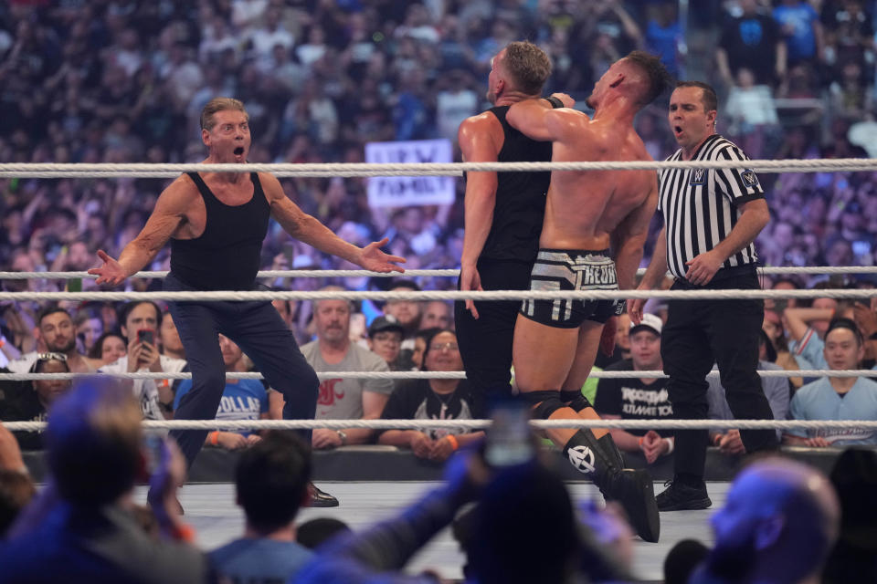 Apr 3, 2022; Arlington, TX, USA; Pat McAfee (center) is attacked by Austin Theory (right) during his match with WWE owner Vince McMahon (left) during WrestleMania at AT&T Stadium. Mandatory Credit: Joe Camporeale-USA TODAY Sports