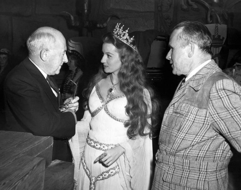 FILE - In this Dec. 16, 1947 file photo, Producer- director Cecil B. DeMille, left, gives actress Rhonda Fleming some advice as Tay Garnett, right, listens in Hollywood, Calif. Actress Rhonda Fleming, the fiery redhead who appeared with Burt Lancaster, Kirk Douglas, Charlton Heston, Ronald Reagan and other film stars of the 1940s and 1950s, has died, Wednesday, Oct. 14, 2020. She was 97. (AP Photo/File)