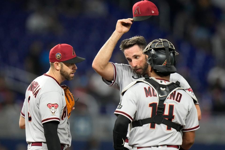 Arizona Diamondbacks starting pitcher Madison Bumgarner, center, stands on the mound with third baseman Evan Longoria, left, and catcher Gabriel Moreno (14) during the fourth inning of a baseball game against the Miami Marlins on April 14, 2023, in Miami.