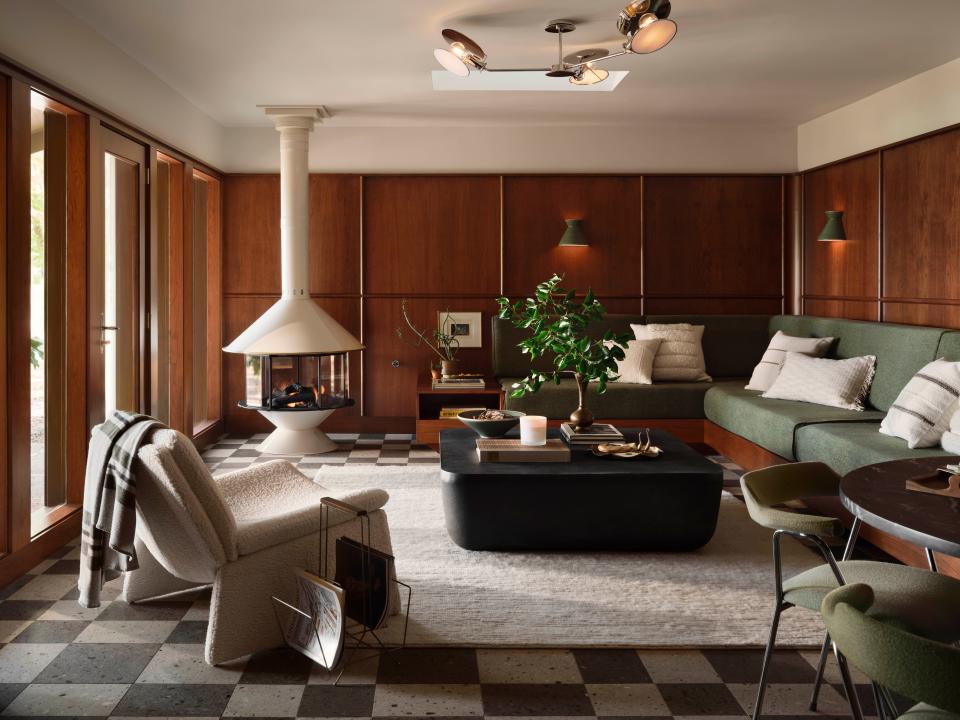 Cherry wood panels with curved radius accents line the walls of the rec room, which is warmed by a retro free-standing fireplace. Black-and-white checkerboard tiles made of pressed volcanic ash line the floors. Skylights were added to increase the natural light.