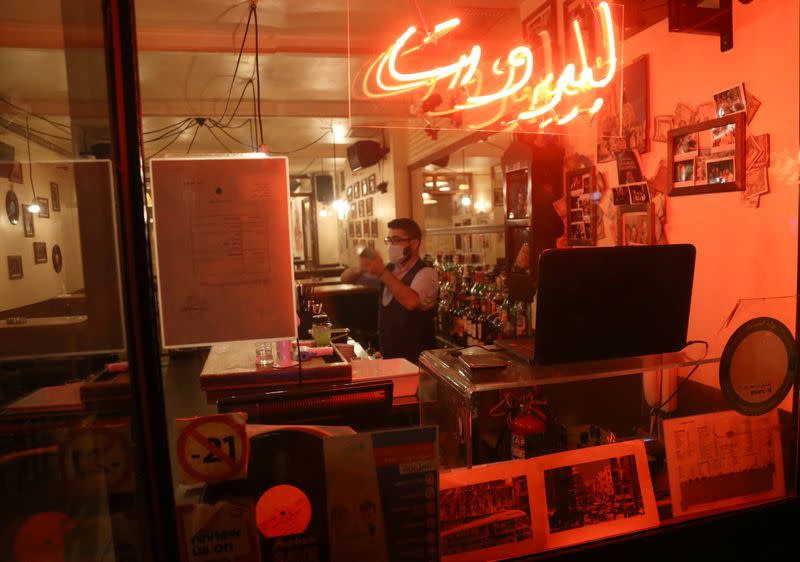 A bartender wearing a protective mask is seen inside a pub in Beirut