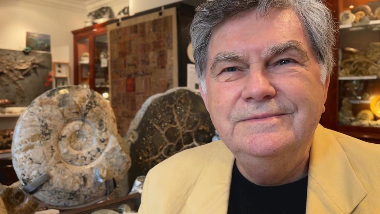 Wolfgang Grulke in his museum sitting next to a large ammonite