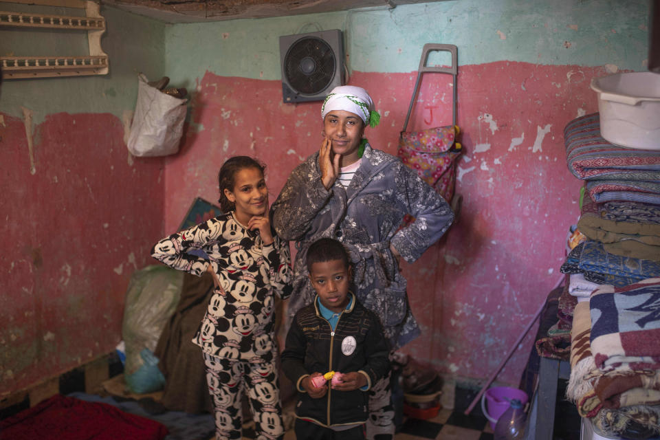 In this in Wednesday, March 25, 2020 photo, Warda, a mother, poses with her son Mohamed and her daughter Jannat in their room in a housing complex in Sale, near Rabat, Morocco. Hundreds of people live in crowded rooms in this Moroccan housing complex with no running water and no income left because of the coronavirus lockdown measures. However volunteers come to help clean as the government tries to protect the population from virus while not punishing the poor. (AP Photo/Mosa'ab Elshamy)