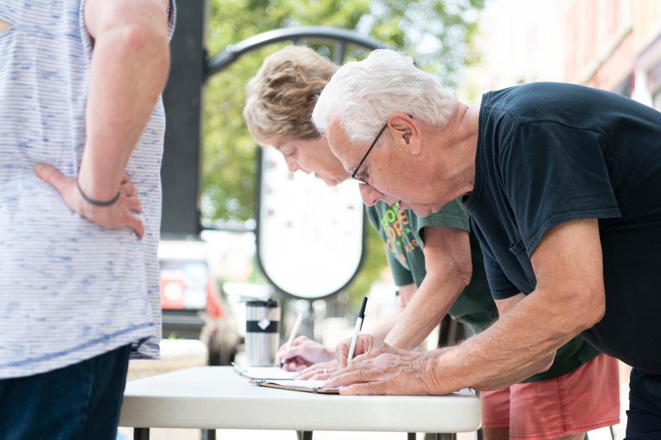 Marshall residents Jim and Claire Hammer sign a petition seeking a city-wide vote on the rezoning of the Marshall Megasite on Tuesday, May 23, 2023.