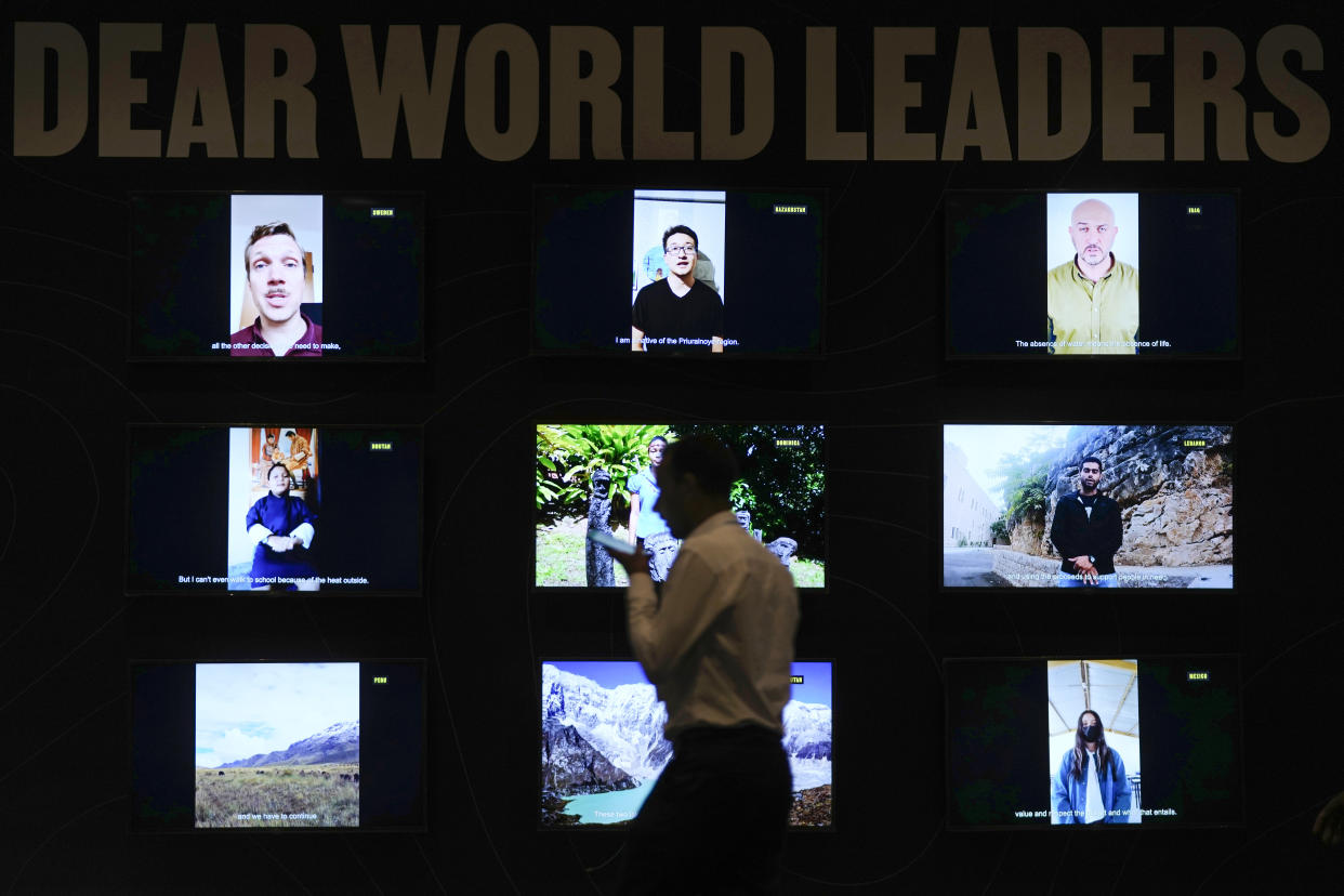 A man walks past a display of videos addressed to world leaders at the COP27 U.N. Climate Summit, Saturday, Nov. 19, 2022, in Sharm el-Sheikh, Egypt. (AP Photo/Peter Dejong)