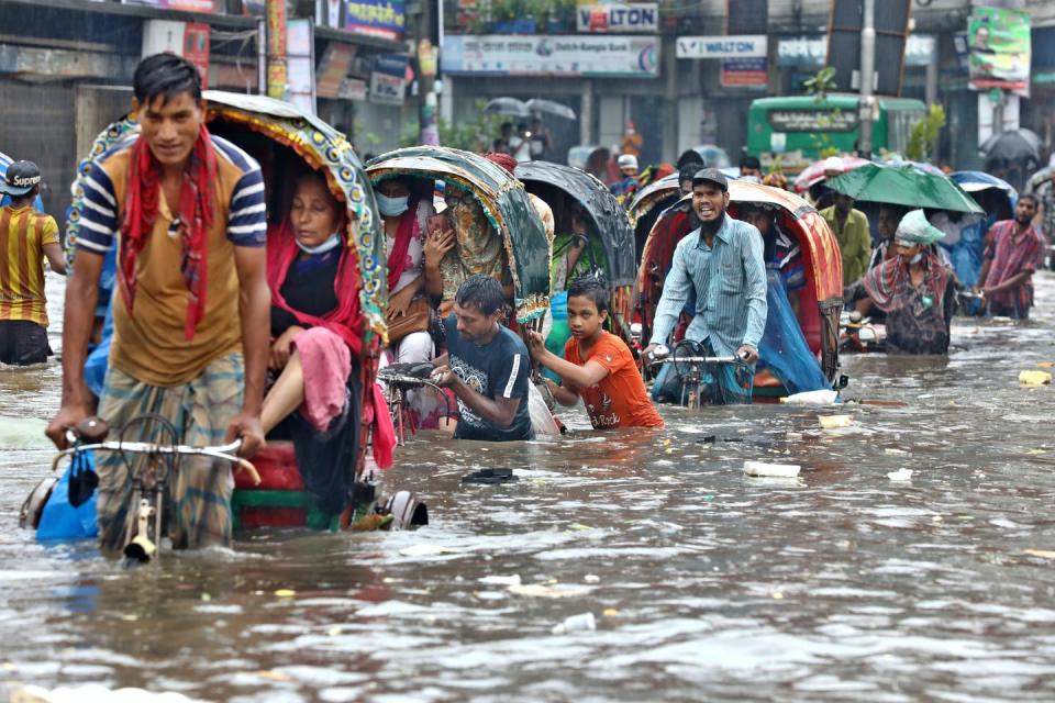 Vehicles try to drive through a flooded street in Dhaka.