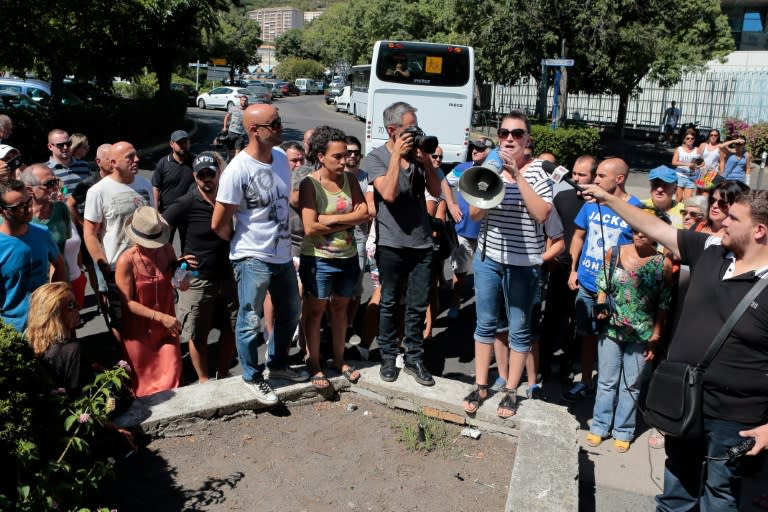 A woman stands next to journalists as she relates on a megaphone the incidents by the creek where has occured a violent fight leaving four wounded in Sisco, on August 14, 2016, on the French Mediterranean island of Corsica
