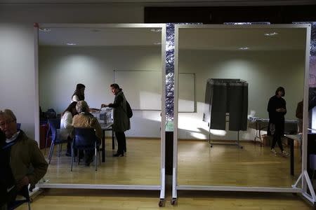 A mirror reflects a woman casting her vote at a polling station during voting in Spain's general election in Pozuelo de Alarcon, near Madrid, Spain, December 20, 2015. REUTERS/Susana Vera