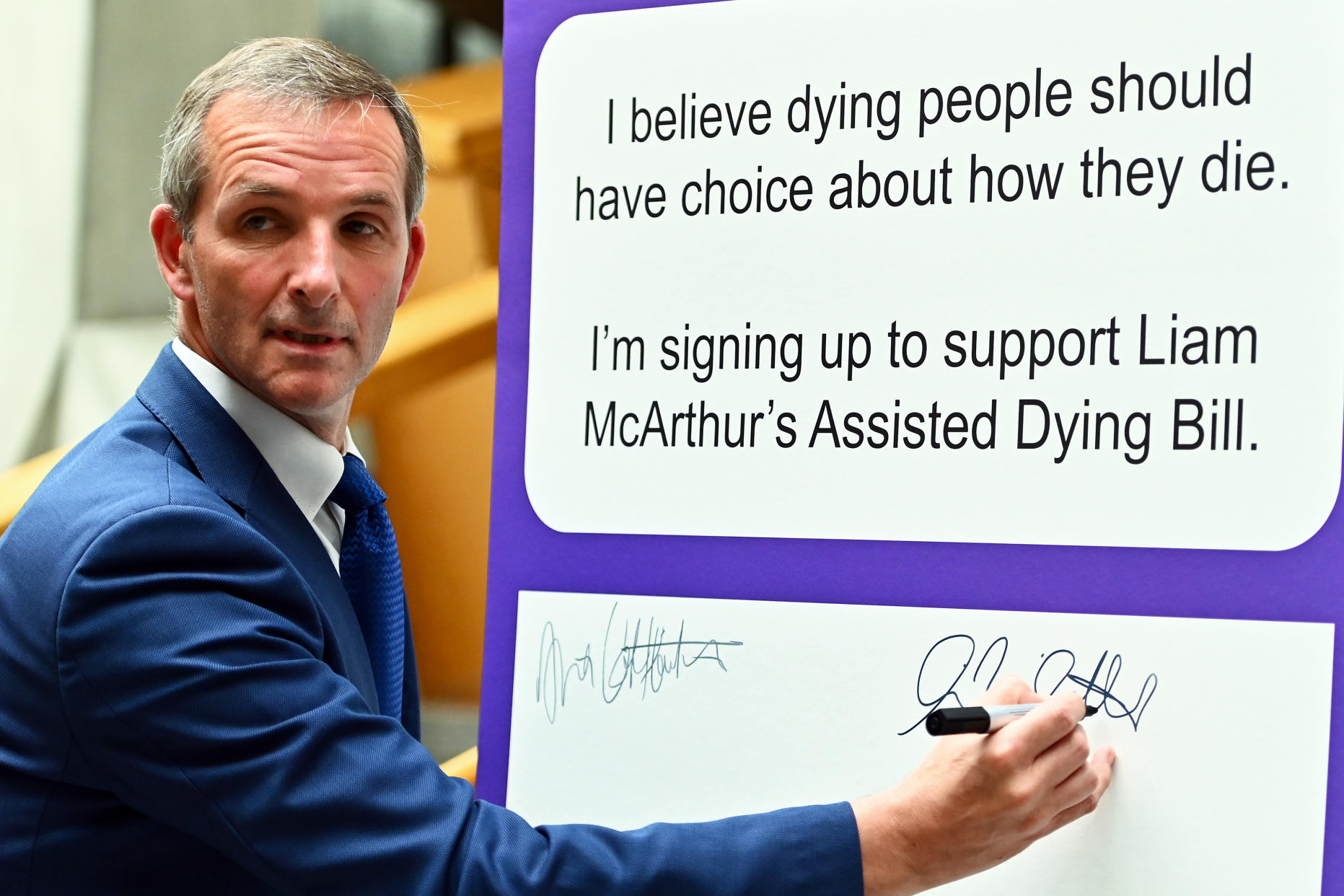 Scottish Liberal Democrat MSP Liam McArthur signs a board in the lobby of the Scottish Parliament for other MSPs to record their support for his Member's Bill on assisted dying, on September 8, 2022 in Edinburgh, Scotland. The Programme for Government is published every year at the beginning of September and sets out the actions to be taken in the coming year. (Photo by Ken Jack/Getty Images)