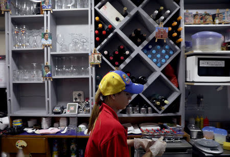 Fiamma, a Venezuelan worker in Spain, wears a cap in the national Venezuelan colours as she walks inside a Venezuelan traditional food restaurant in Madrid, Spain, May 16, 2018. REUTERS/Sergio Perez