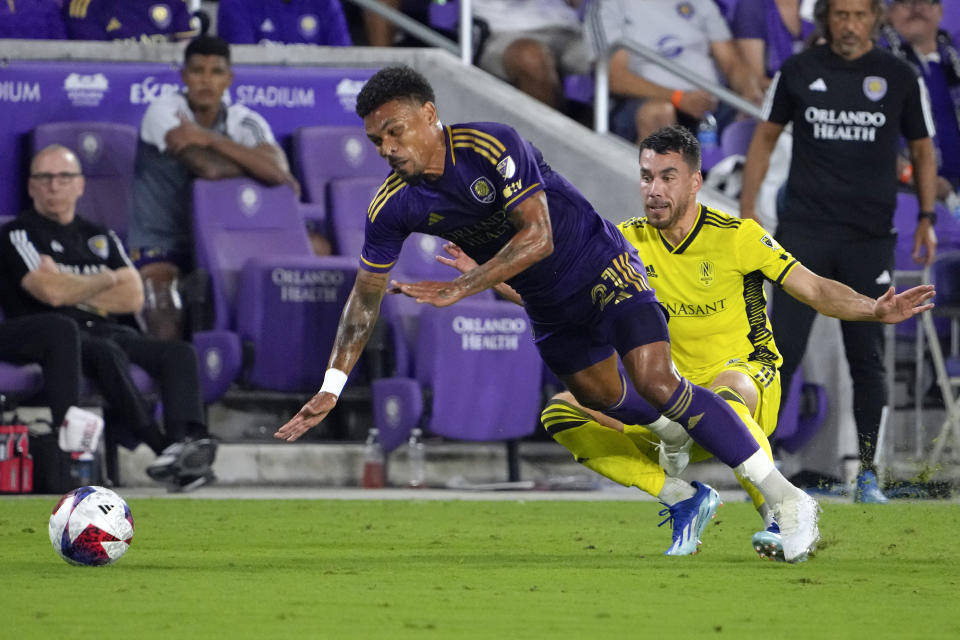 Nashville SC defender Daniel Lovitz, right, trips Orlando City midfielder Junior Urso, left, during the second half of an MLS playoff soccer match, Monday, Oct. 30, 2023, in Orlando, Fla. Lovitz was given a yellow card on the play. (AP Photo/John Raoux)