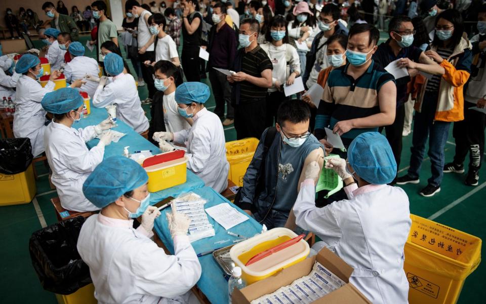 University students in Wuhan queue to receive the China National Biotec Group (CNBG) vaccine - AFP