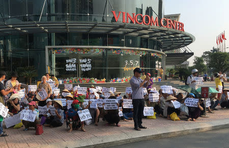 Farmers from Duong Noi village sit in front of a shopping mall outside a court while they protest during a trial of Can Thi Theu, a farmer and land protection activist in Hanoi, Vietnam September 20, 2016. The placards read "Can Thi Theu is innocent", "Justice for innocent Can Thi Theu" and "make arrest - grabbing land is criminal". REUTERS/Nguyen Tien Thinh