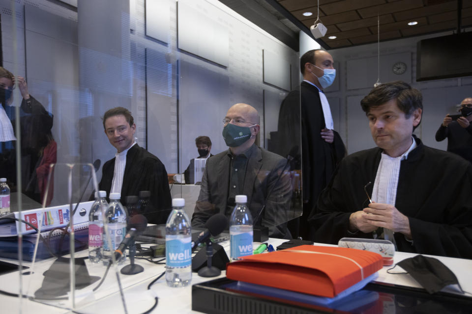 Lawyers for Shell, rear, pass Milieudefensie director Donald Pols, center, and lawyer Roger Cox, right, at the start of the court case of Milieudefensie, the Dutch arm of the Friends of the Earth environmental organization, against Shell in The Hague, Netherlands, Tuesday, Dec. 1, 2020. A landmark legal battle opened as climate change activists in the Netherlands go to court seeking an order for energy giant Shell to rein in its carbon emissions. (AP Photo/Peter Dejong, Pool)