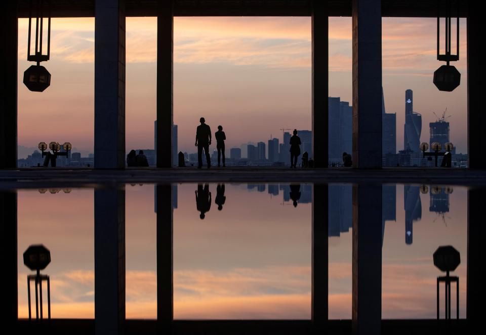 People are reflected in a puddle as they watch the sunset in Moscow, Russia May 27, 2021.