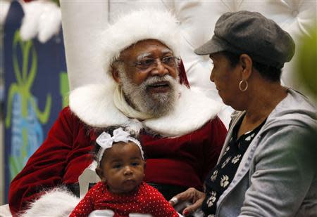 African American Santa Claus Langston Patterson (L), 77, poses with four-month-old Raelyn Price and her grandmother Gloria Boissiere, at Baldwin Hills Crenshaw Plaza mall in Los Angeles, California, December 16, 2013. REUTERS/Lucy Nicholson